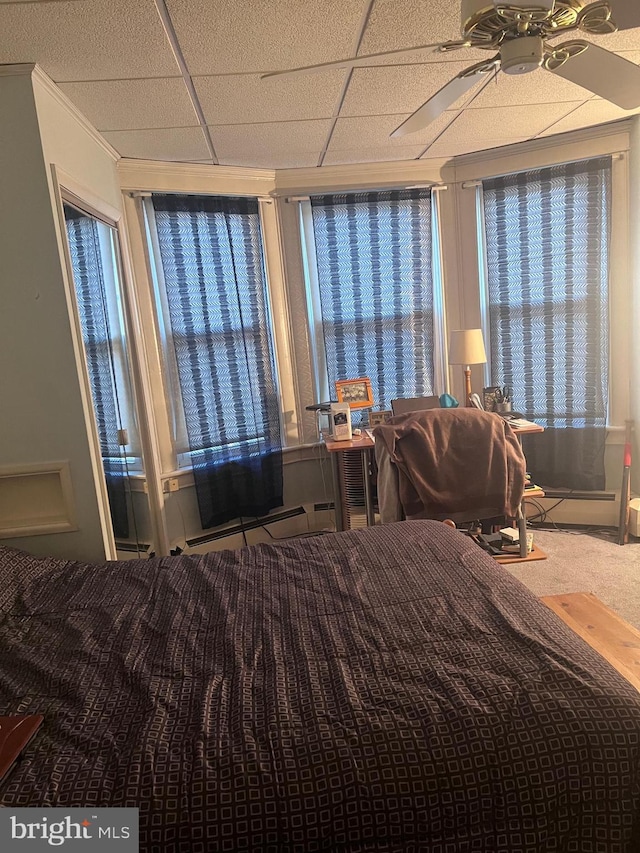 unfurnished bedroom featuring a baseboard heating unit, crown molding, carpet floors, and a paneled ceiling