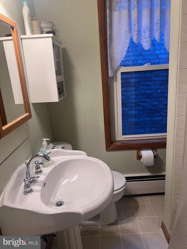 bathroom featuring a baseboard heating unit, sink, tile patterned floors, and toilet