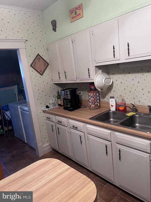 kitchen with white cabinetry, dark tile patterned flooring, washer / dryer, and sink