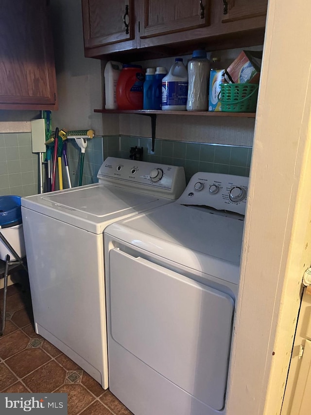 laundry area featuring separate washer and dryer, dark tile patterned flooring, cabinets, and tile walls