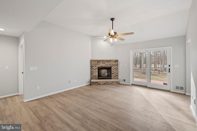 unfurnished living room featuring ceiling fan, a brick fireplace, and light hardwood / wood-style floors