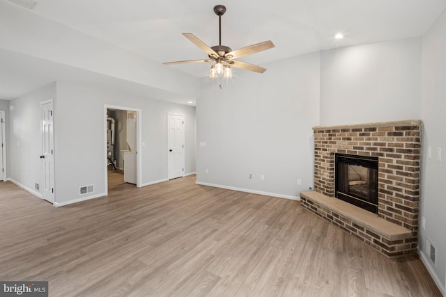 unfurnished living room featuring ceiling fan, a fireplace, and light hardwood / wood-style floors