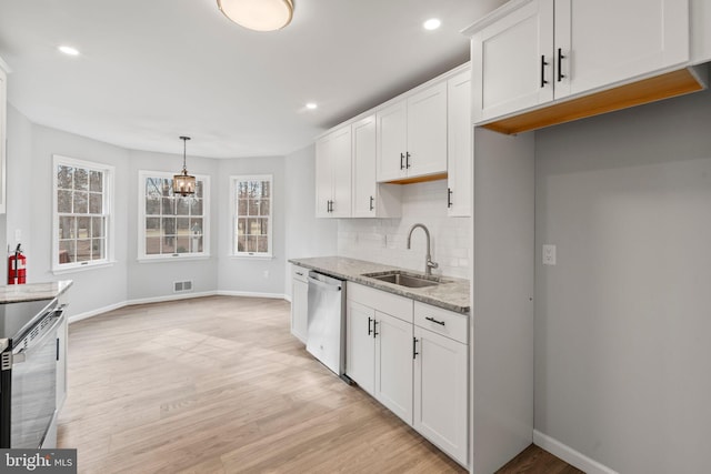 kitchen with sink, appliances with stainless steel finishes, light stone countertops, white cabinets, and decorative light fixtures