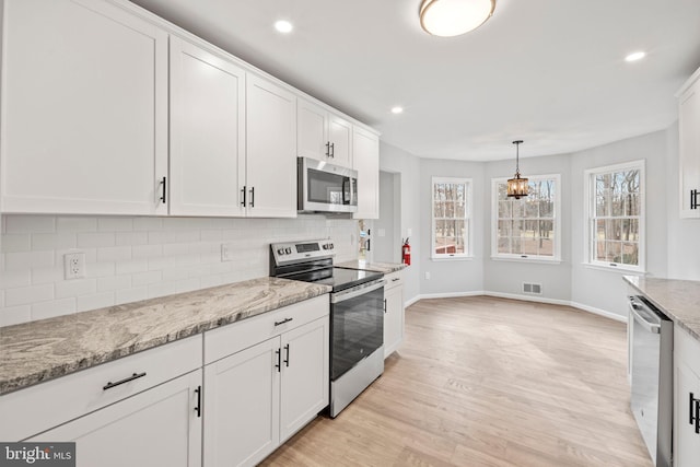 kitchen with white cabinetry, light stone countertops, and appliances with stainless steel finishes