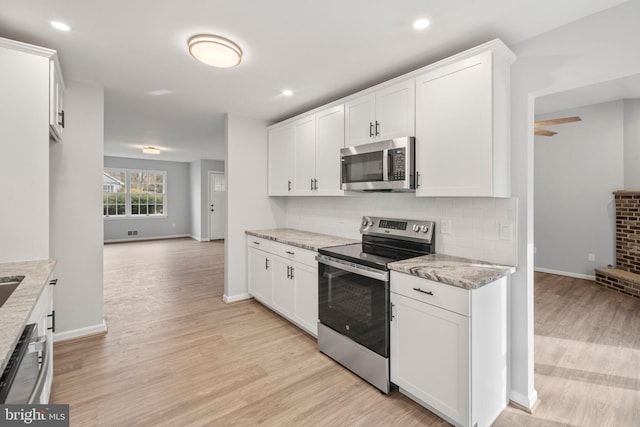 kitchen with light stone countertops, appliances with stainless steel finishes, and white cabinets