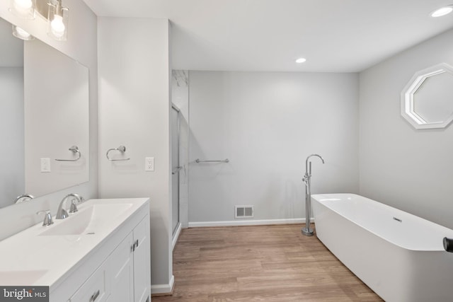 bathroom featuring wood-type flooring, shower with separate bathtub, and vanity