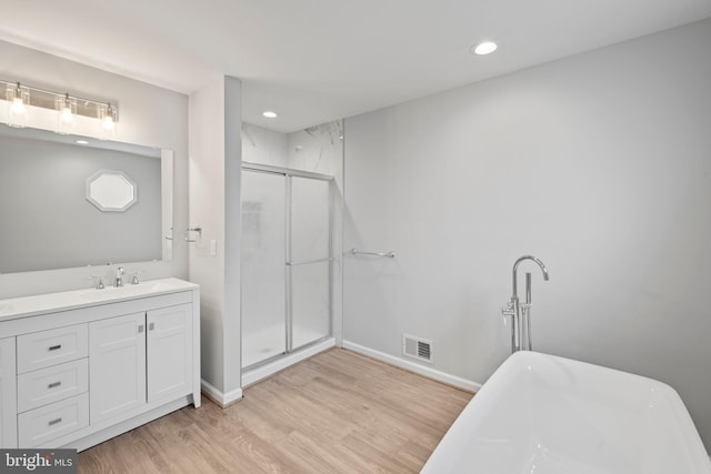 bathroom with plus walk in shower, hardwood / wood-style floors, and vanity