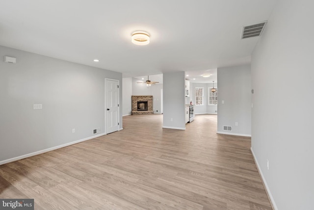 unfurnished living room featuring ceiling fan, a fireplace, and light hardwood / wood-style flooring