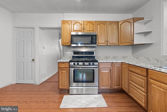 kitchen with light stone counters, light hardwood / wood-style floors, and appliances with stainless steel finishes