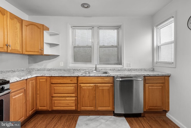 kitchen with light stone counters, appliances with stainless steel finishes, light hardwood / wood-style floors, and sink