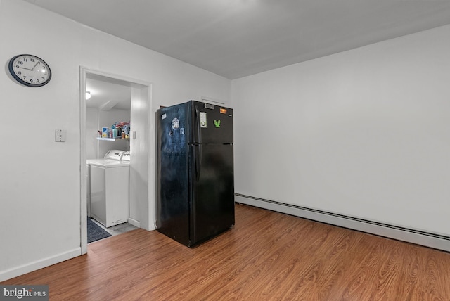 kitchen with black refrigerator, independent washer and dryer, light hardwood / wood-style flooring, and a baseboard heating unit