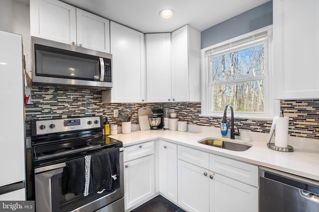 kitchen featuring white cabinetry, stainless steel appliances, backsplash, and sink