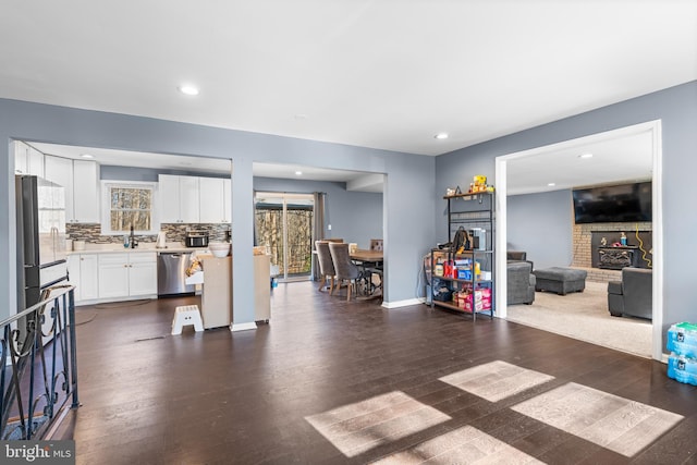 living room featuring a brick fireplace and dark hardwood / wood-style flooring