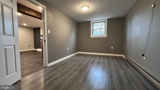 empty room featuring baseboard heating and dark hardwood / wood-style floors