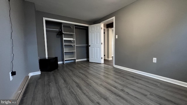 unfurnished bedroom with dark hardwood / wood-style floors, a closet, and a baseboard heating unit