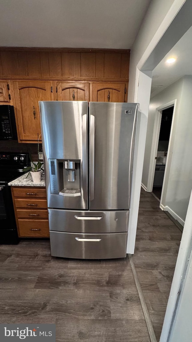 kitchen featuring black / electric stove, dark wood-type flooring, light stone countertops, and stainless steel refrigerator with ice dispenser