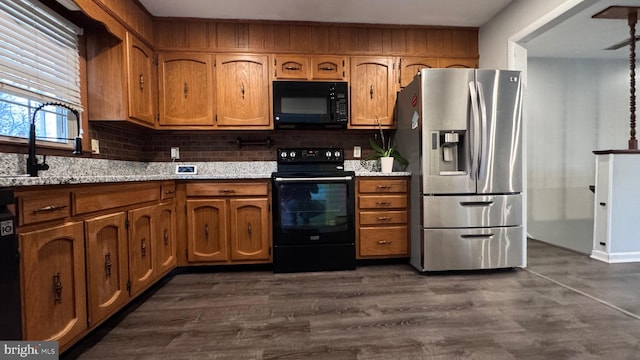 kitchen with dark hardwood / wood-style flooring, light stone countertops, sink, and black appliances