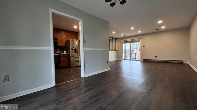 empty room featuring dark hardwood / wood-style flooring and a baseboard heating unit