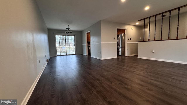 unfurnished living room featuring dark hardwood / wood-style floors and a notable chandelier