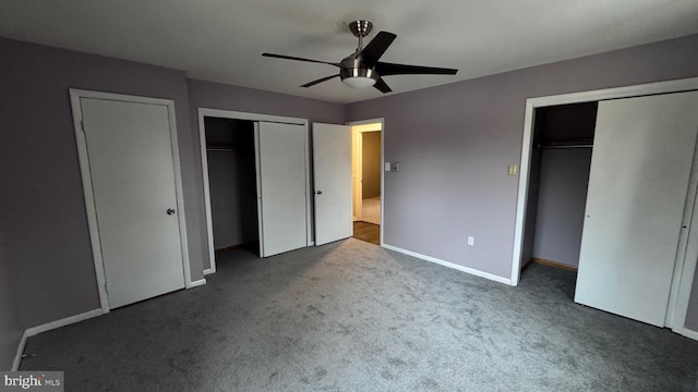 unfurnished bedroom featuring multiple closets, dark colored carpet, and ceiling fan