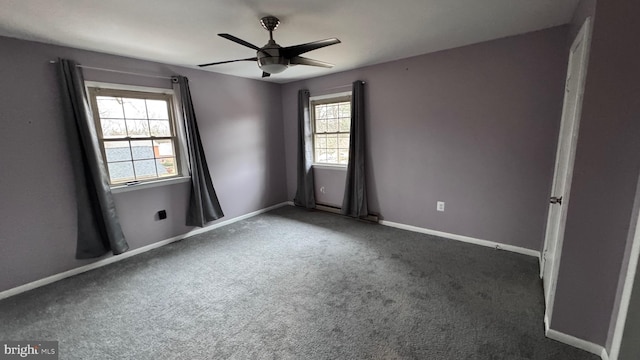 spare room with dark colored carpet and ceiling fan