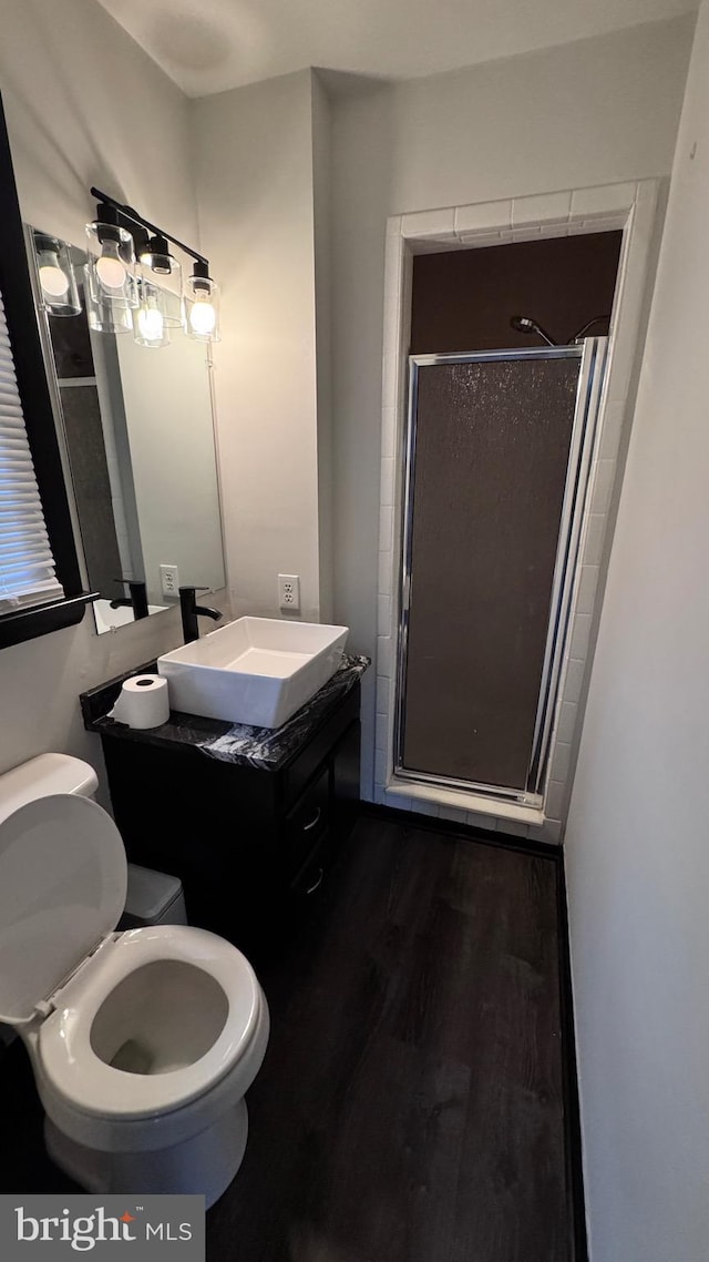 bathroom with an enclosed shower, vanity, wood-type flooring, and toilet