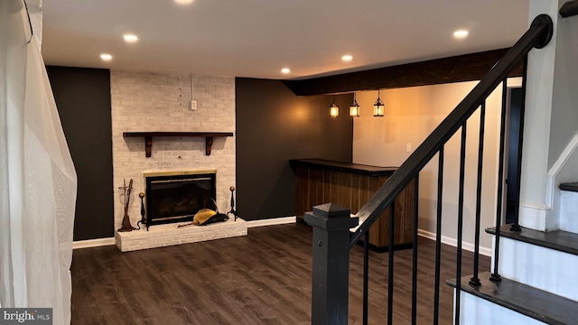 staircase with wood-type flooring and a brick fireplace