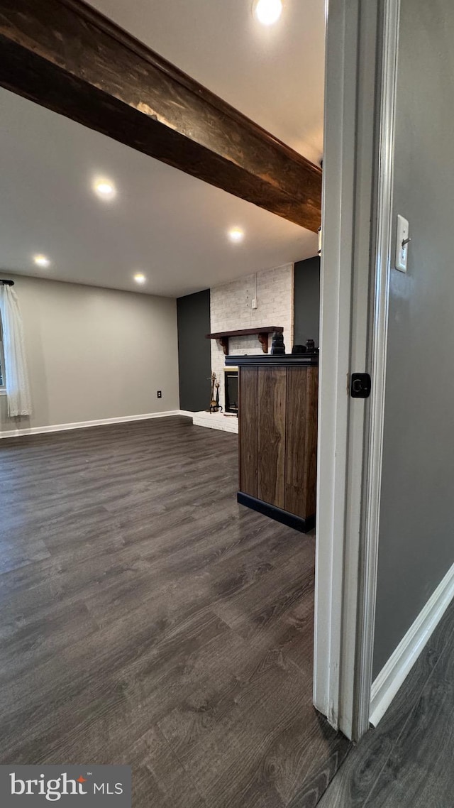 interior space with beamed ceiling, a fireplace, and dark hardwood / wood-style flooring