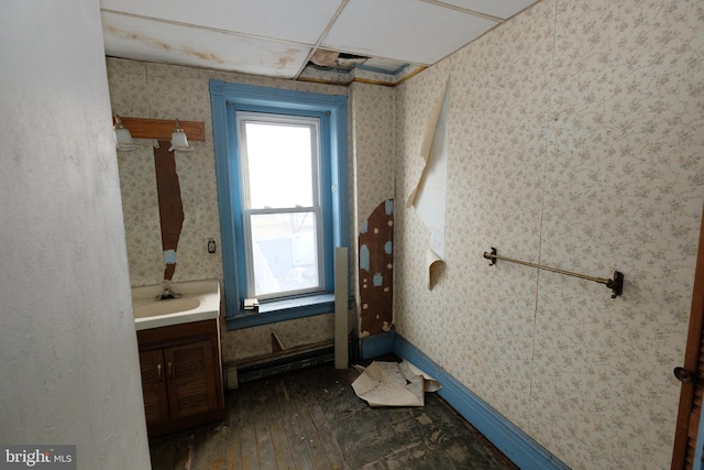 bathroom with wallpapered walls, baseboards, hardwood / wood-style flooring, and vanity