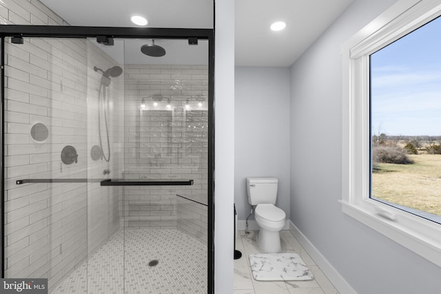 bathroom featuring walk in shower, toilet, and a wealth of natural light