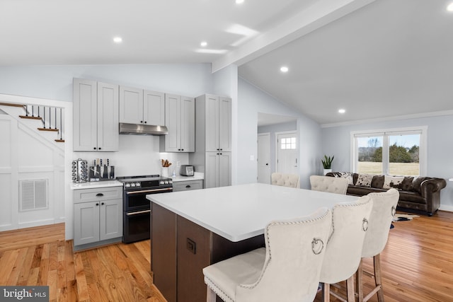 kitchen featuring double oven range, a kitchen breakfast bar, a center island, and gray cabinetry