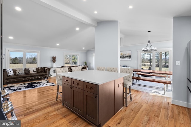 kitchen with lofted ceiling with beams, a kitchen island, a breakfast bar, and decorative light fixtures