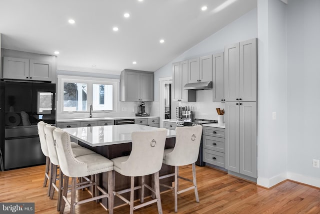 kitchen with black fridge, a breakfast bar, gray cabinets, and a center island