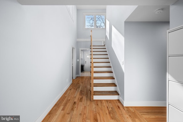 staircase featuring hardwood / wood-style floors and a towering ceiling