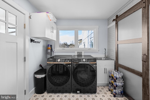 washroom featuring cabinets, a barn door, sink, and washing machine and clothes dryer