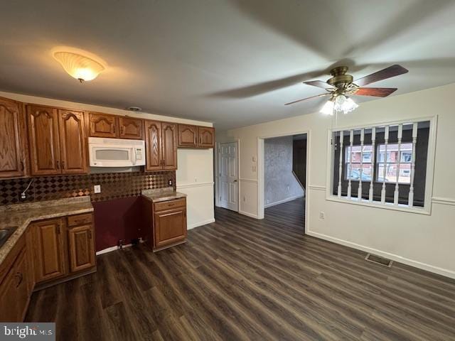 kitchen with dark wood-type flooring, backsplash, and ceiling fan