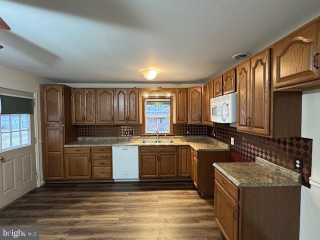 kitchen with light stone countertops, sink, dark wood-type flooring, and white appliances