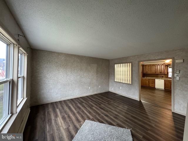 unfurnished living room featuring dark hardwood / wood-style flooring and a textured ceiling