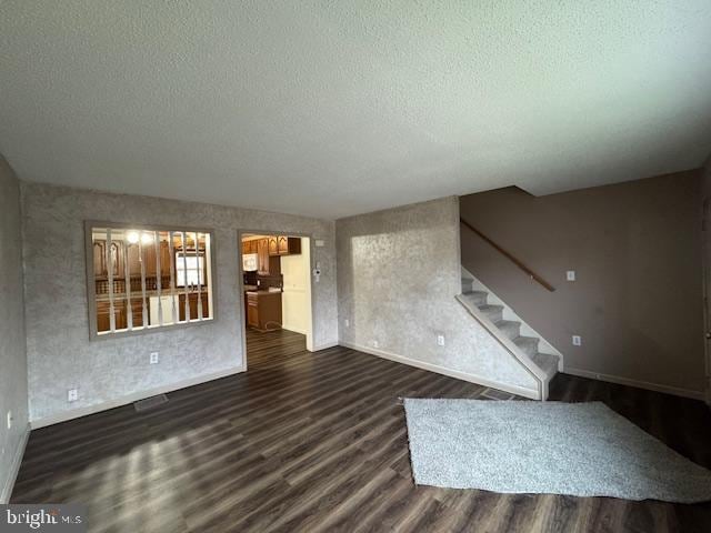 unfurnished living room with dark wood-type flooring and a textured ceiling