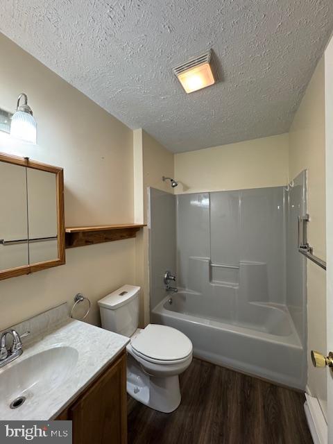 full bathroom with wood-type flooring, vanity,  shower combination, toilet, and a textured ceiling