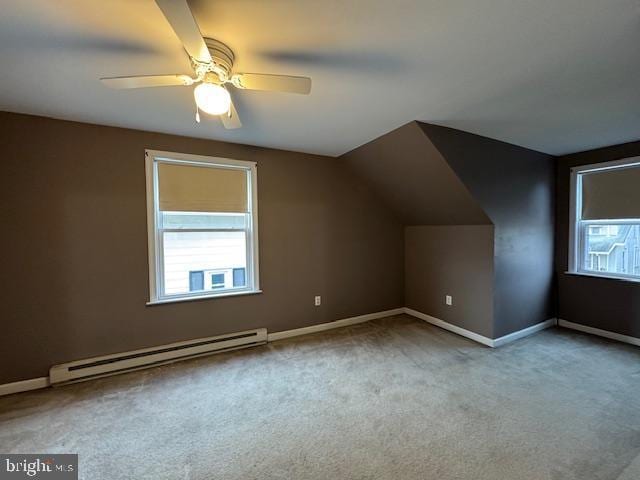 additional living space featuring baseboard heating, light colored carpet, ceiling fan, and a wealth of natural light