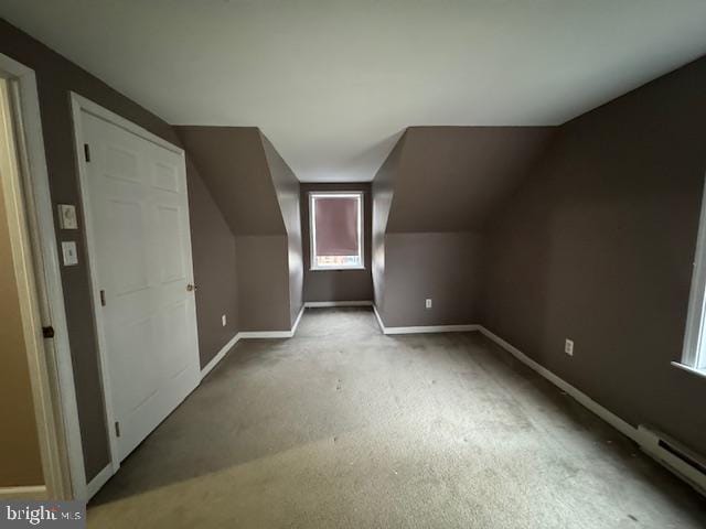 additional living space with vaulted ceiling, carpet, and a baseboard heating unit