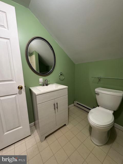 bathroom featuring vaulted ceiling, a baseboard radiator, vanity, toilet, and tile patterned floors