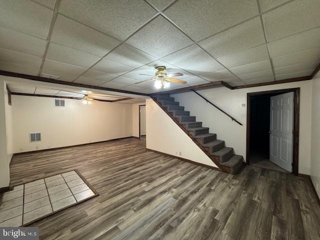 basement featuring hardwood / wood-style flooring, a paneled ceiling, and ceiling fan