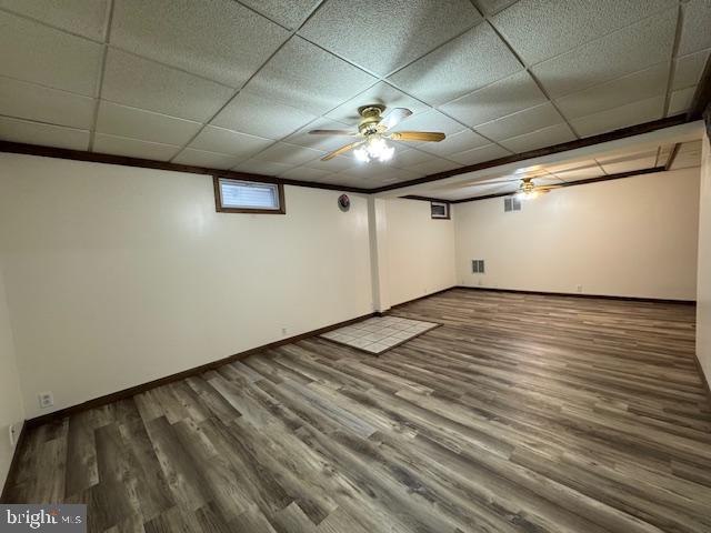 basement with wood-type flooring, a drop ceiling, and ceiling fan