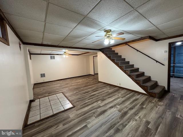 basement with hardwood / wood-style flooring, a paneled ceiling, and ceiling fan