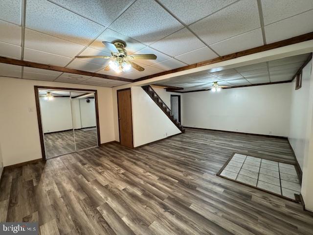 basement with ceiling fan, wood-type flooring, and a drop ceiling