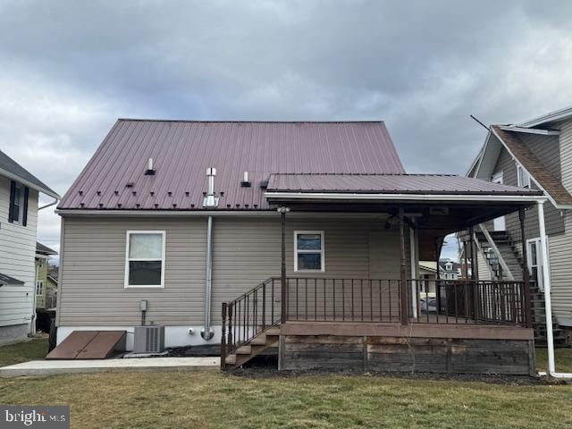 rear view of house featuring cooling unit and a yard