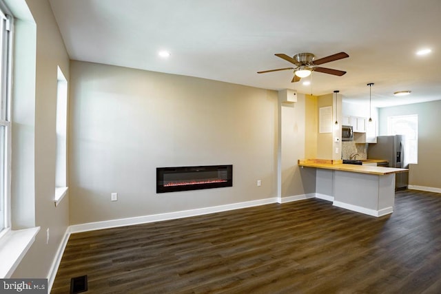 unfurnished living room featuring dark hardwood / wood-style floors and ceiling fan