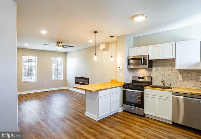 kitchen featuring hanging light fixtures, white cabinetry, appliances with stainless steel finishes, and butcher block counters